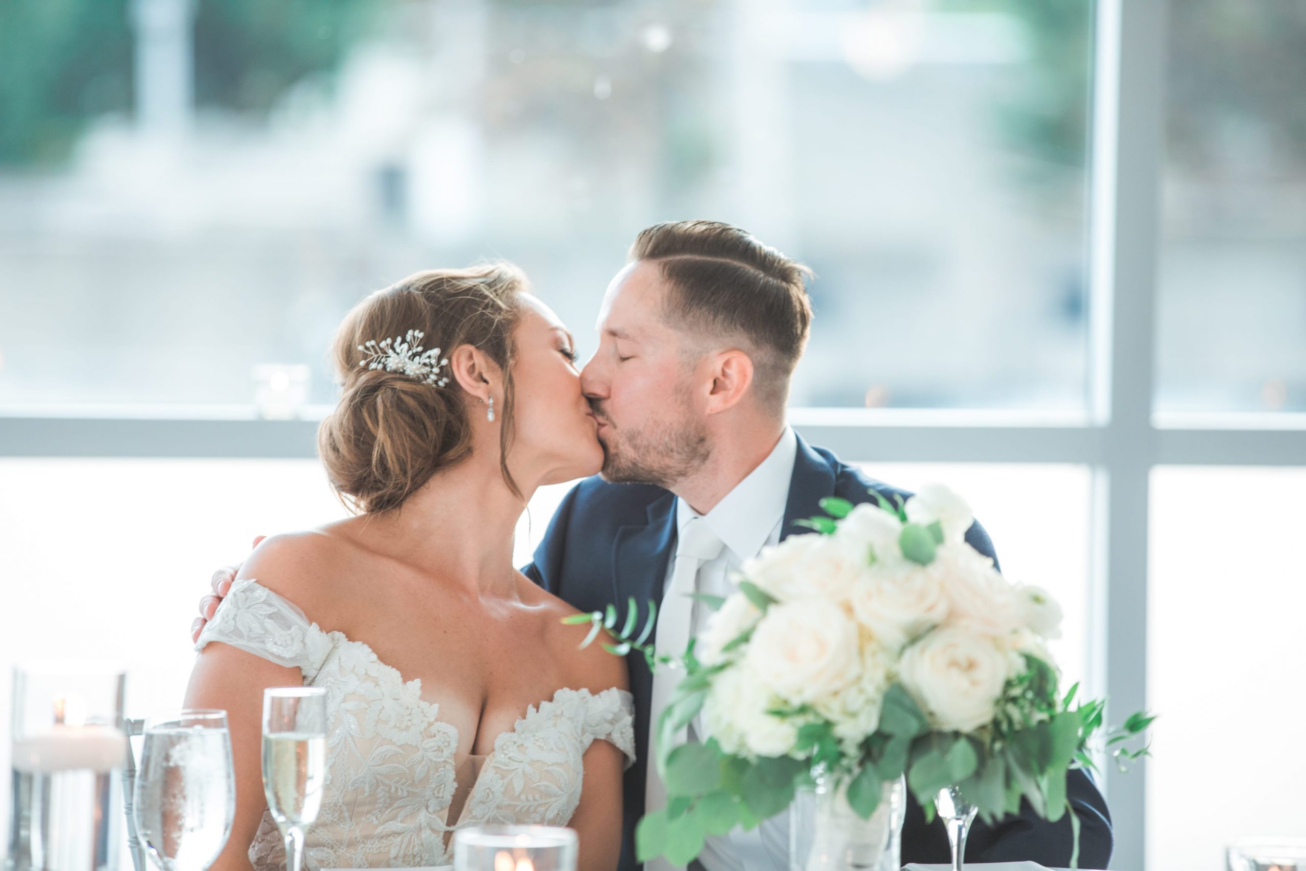 Real Detroit Wedding - Mike Staff Productions bride and groom kissing at head table