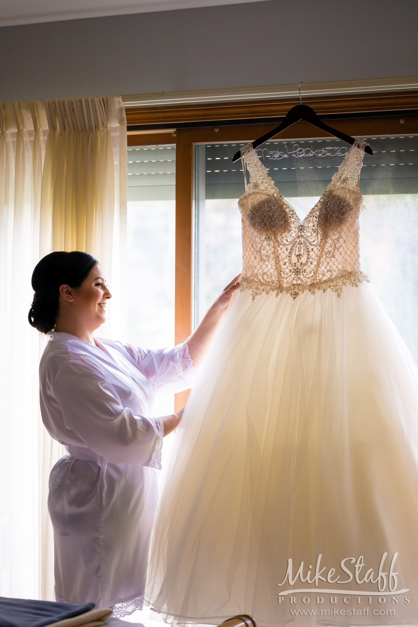 bride looking at hanging wedding dress - Mike Staff Productions bride looking at hanging wedding dress